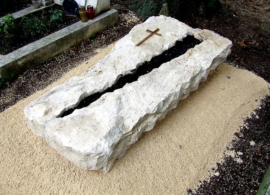 Egyedi monolit mészkő sziklasírkő bronz kereszttel, hasított természetes formával