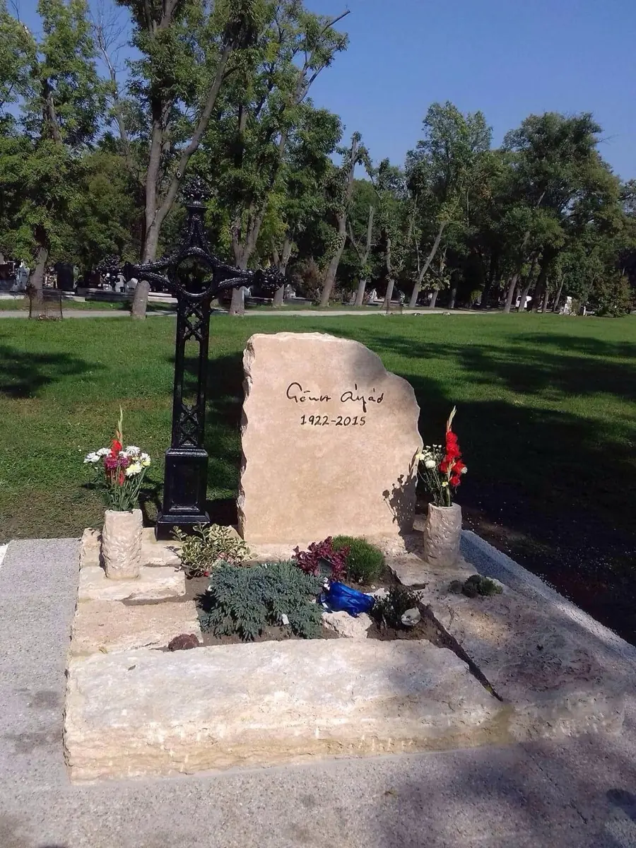 Rusztikus mészkő sírkő kovácsoltvas kereszttel, kővázákkal és virágokkal díszítve