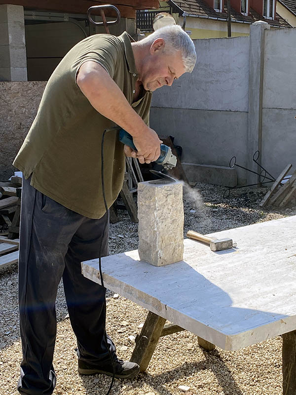 Rest István mészkő kővázát csiszol a műhelyudvaron